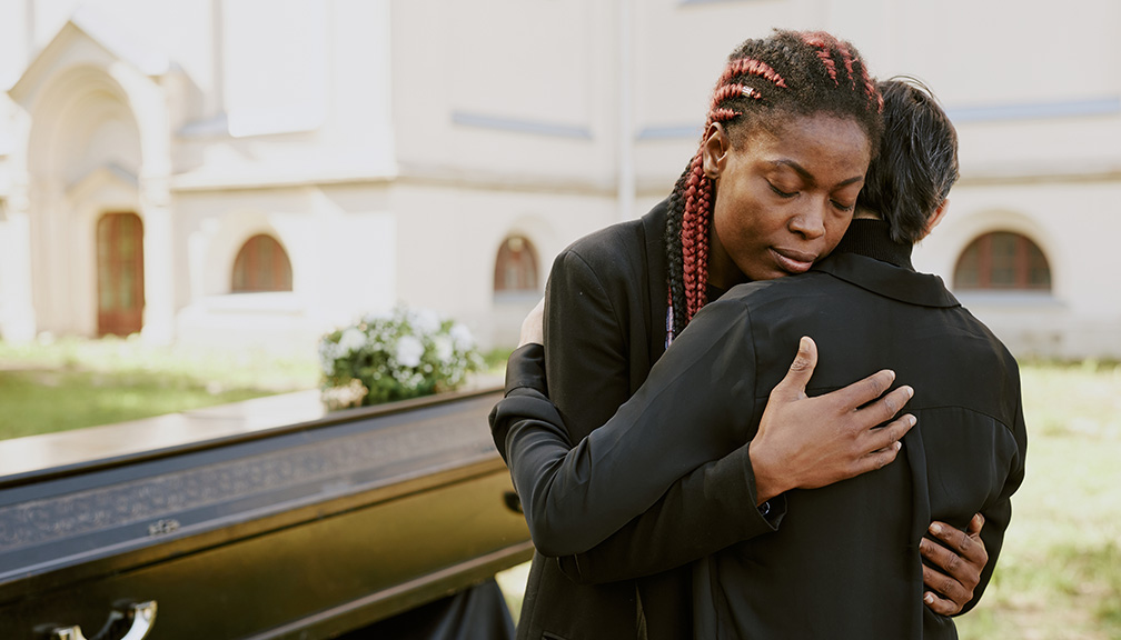 Photo of Woman Hugging Someone in Front of Casket