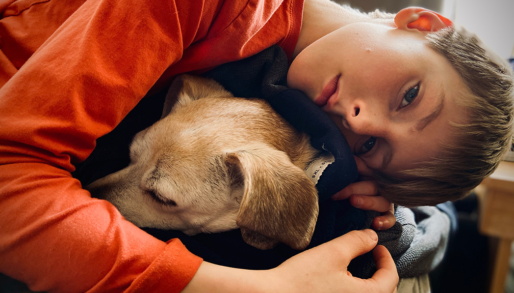 Photo of Boy Curled Up With His Dog